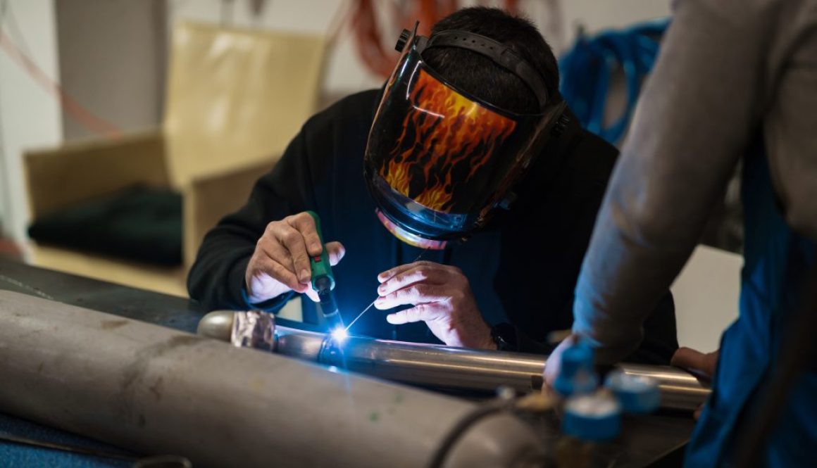 Man working with argon welding machine in a garage